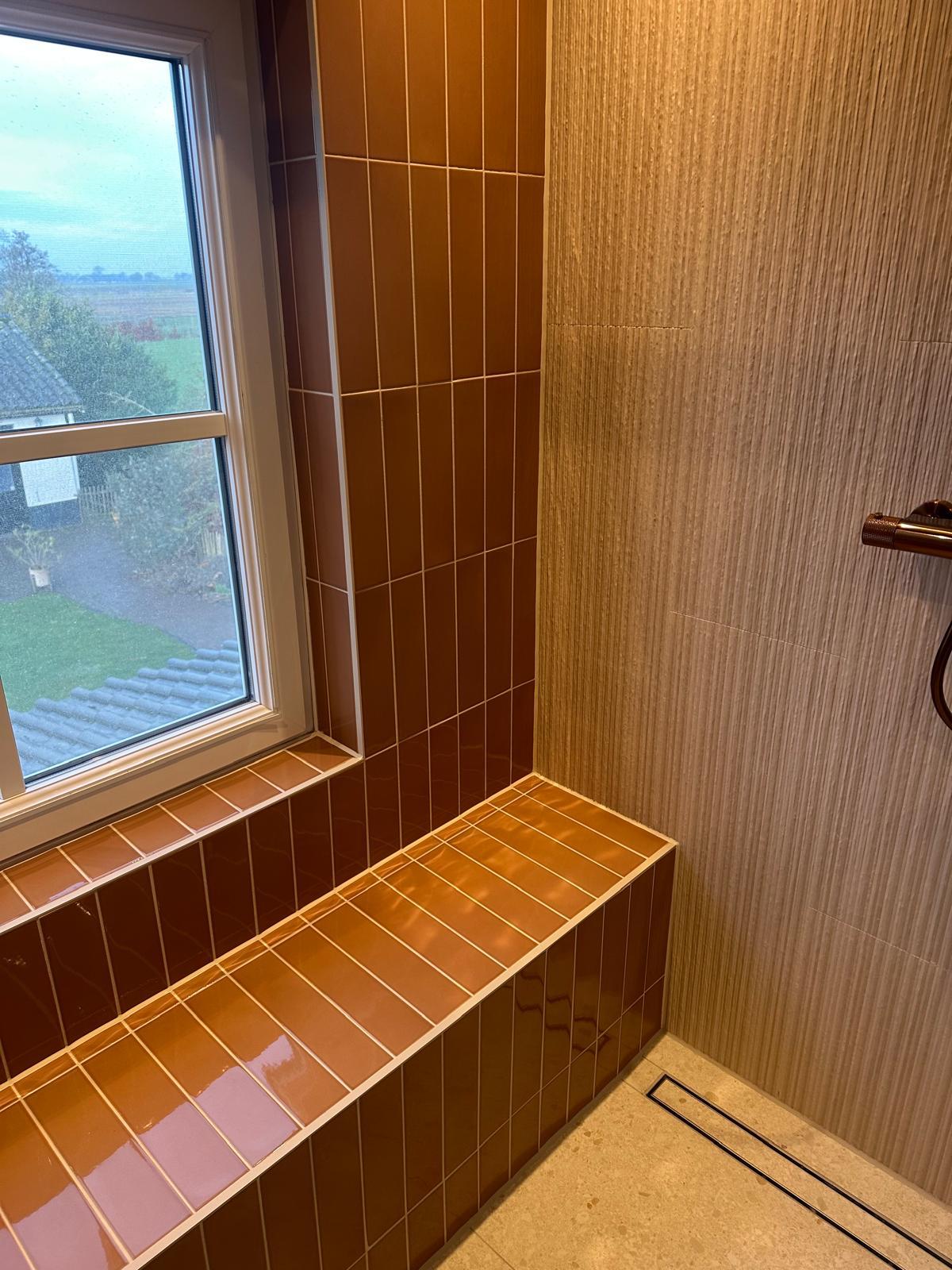 Douche met oranje tegels en tegelbankje